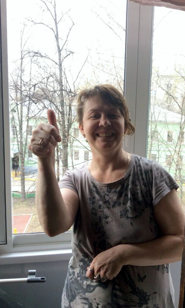 Женщина с поднятым большим пальцем у окна