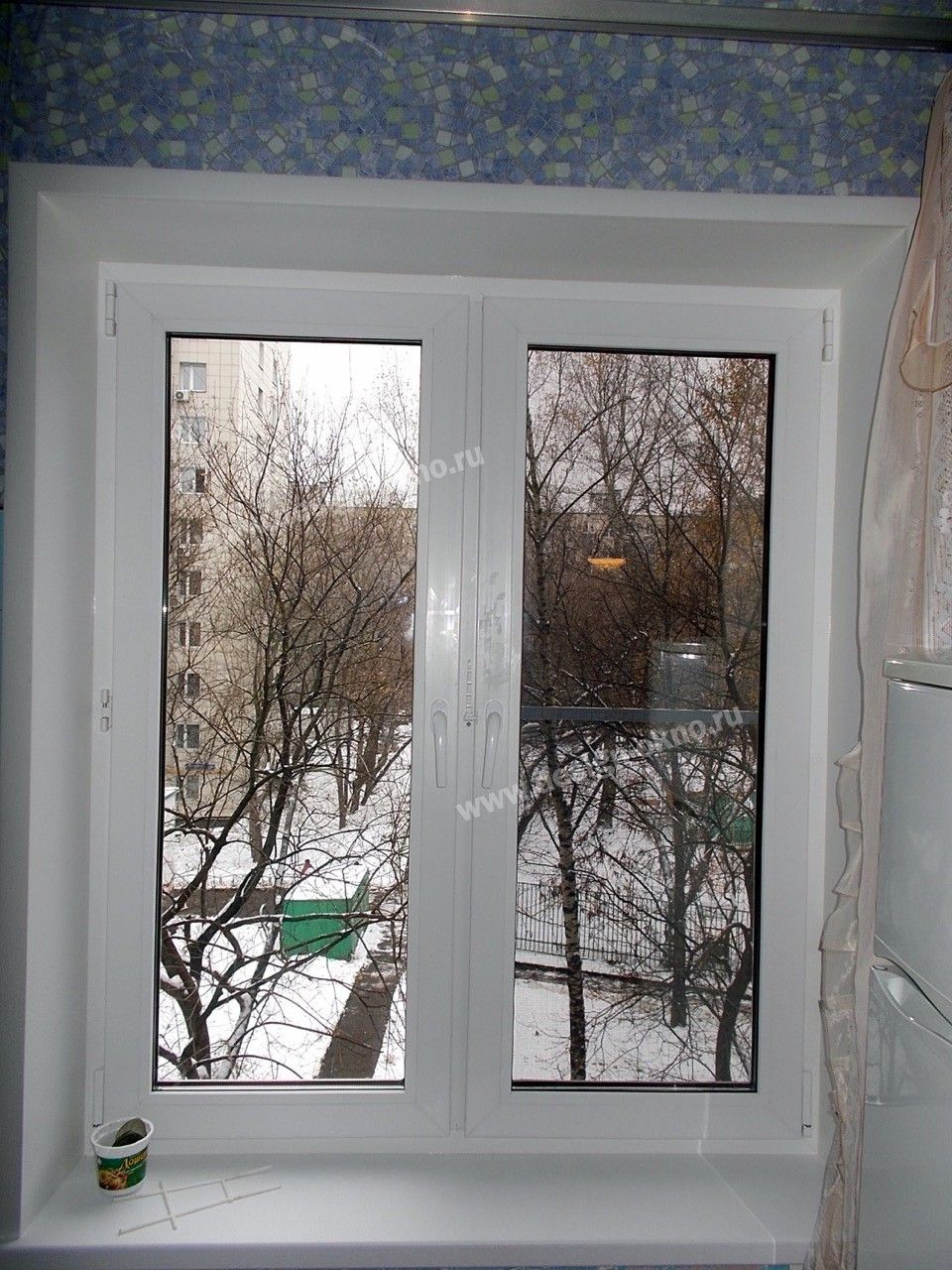 Белое пластиковое окно с видом на деревья.