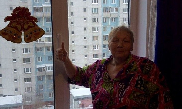 Довольная пожилая женщина у пластикового окна