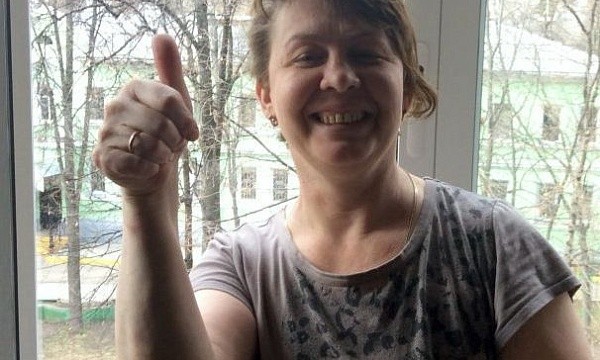 Женщина с поднятым большим пальцем у окна