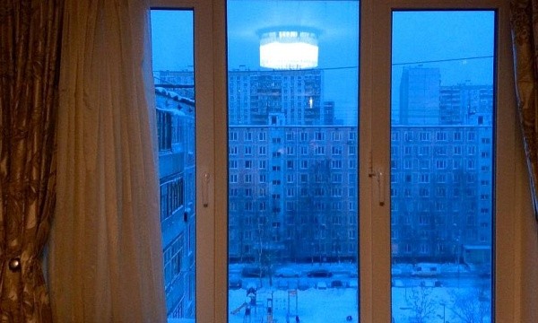 Окно с видом на многоэтажки и детскую