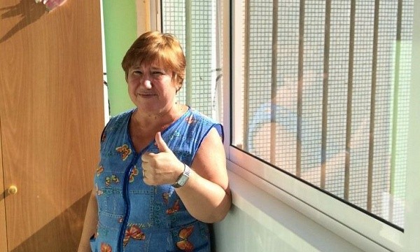 Довольная женщина в синем платье у окна